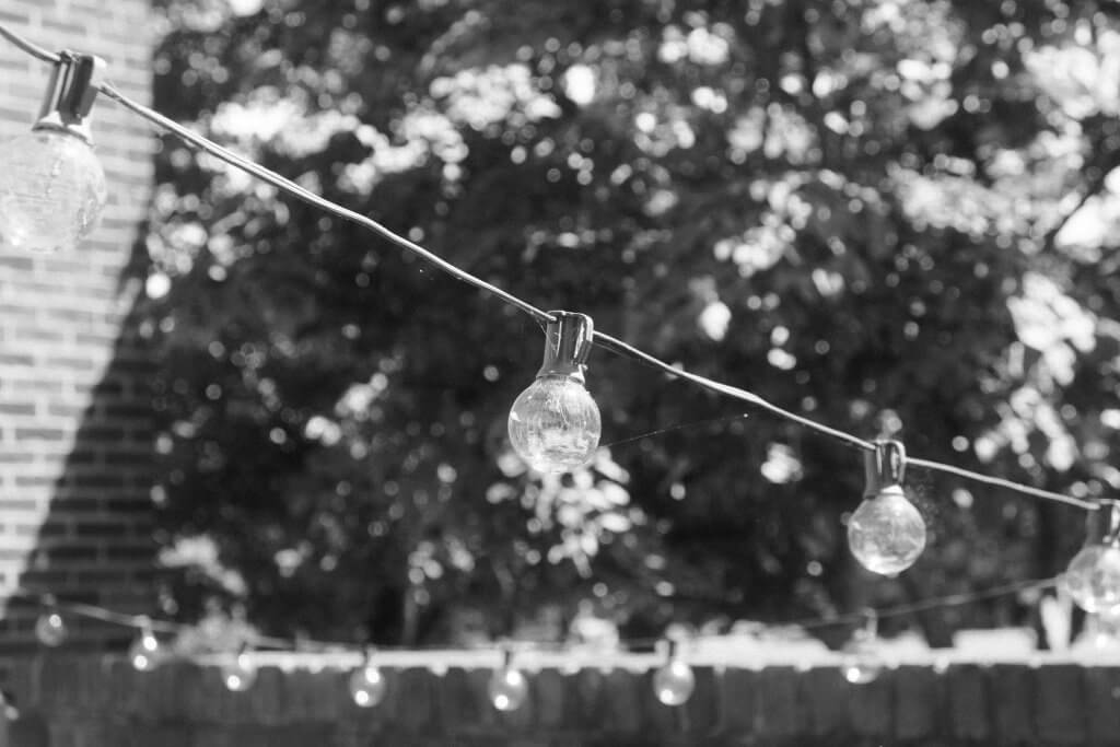 A string of incandescent light bulbs in a backyard.